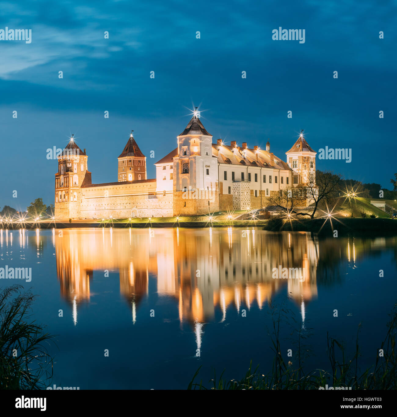 Mir, Bielorussia. Una vista pittoresca del complesso del Castello di Mir In brillante illuminazione serale con candelette di riflessioni sul lago di acqua. Famoso punto di riferimento, antica Gothi Foto Stock