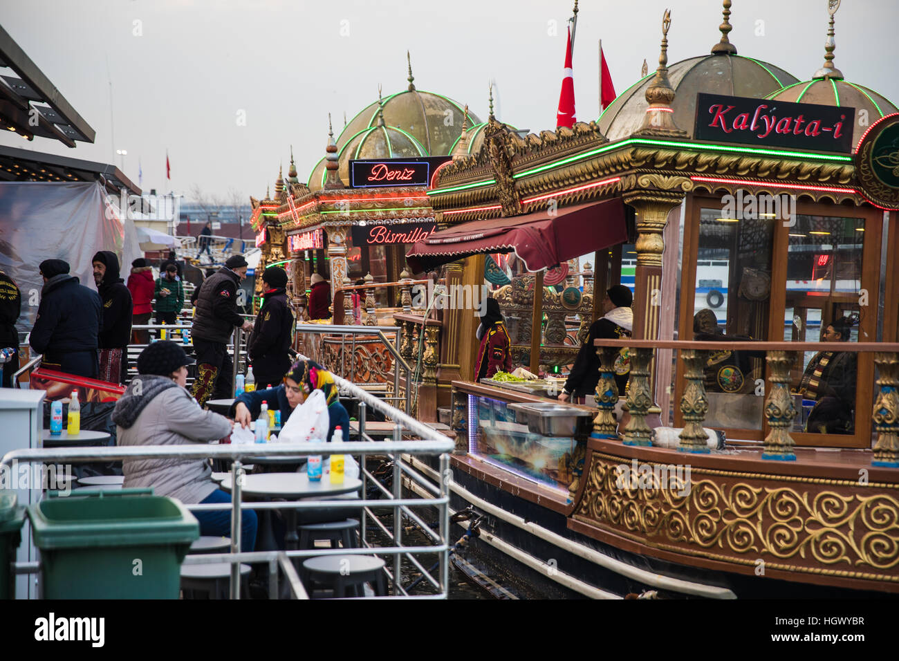 La gente mangia Balik Ekmek ("Pesce nel pane"), cucinati e serviti da colorate e imbarcazioni decorate a Istanbul. Foto Stock