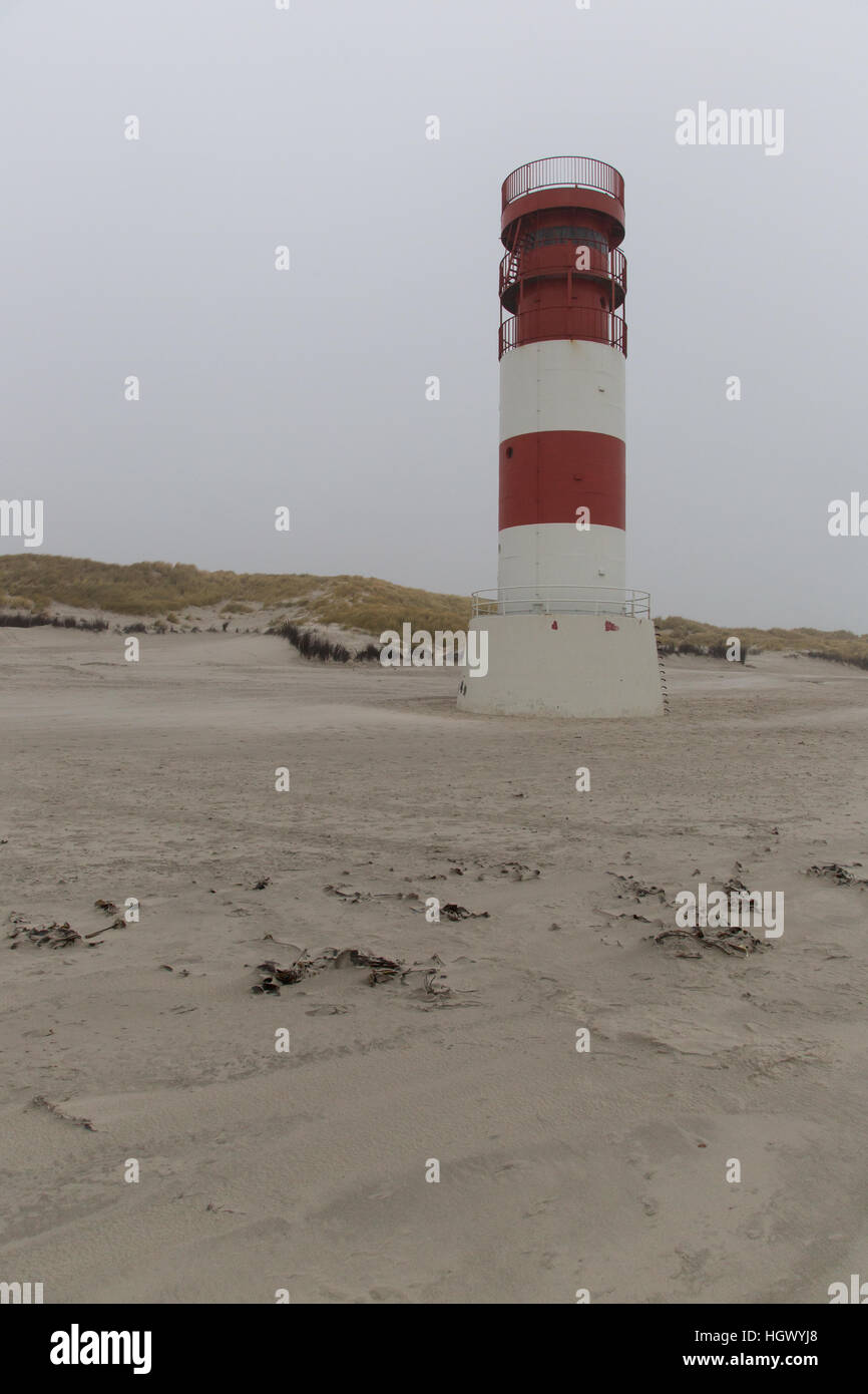 Bianco Rosso faro sulla spiaggia di sabbia con scuri meteo Foto Stock