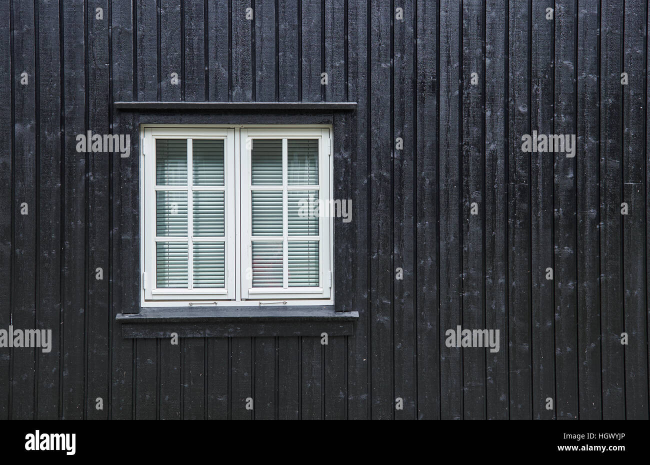 Bianco finestra a battente con montanti e tende all'interno e fissata in un bordo nero e listello parete in legno Foto Stock