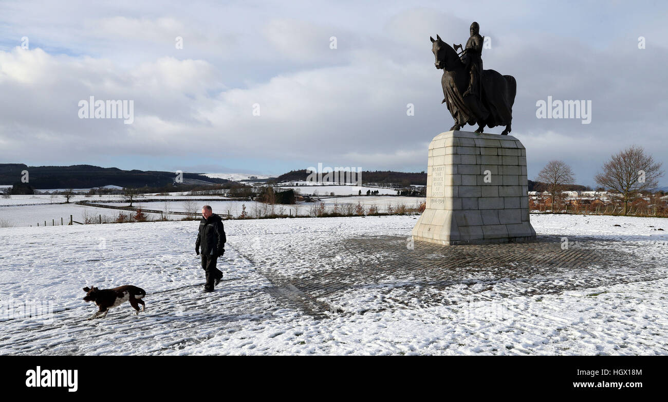 Un dog walker nella neve vicino a Robert the Bruce statua in Bannockburn, dopo il Met Office emessi avvisi di maltempo in tutta l'Inghilterra, Scozia, Galles e Irlanda del Nord per le combinazioni di forte vento, neve e ghiaccio. Foto Stock