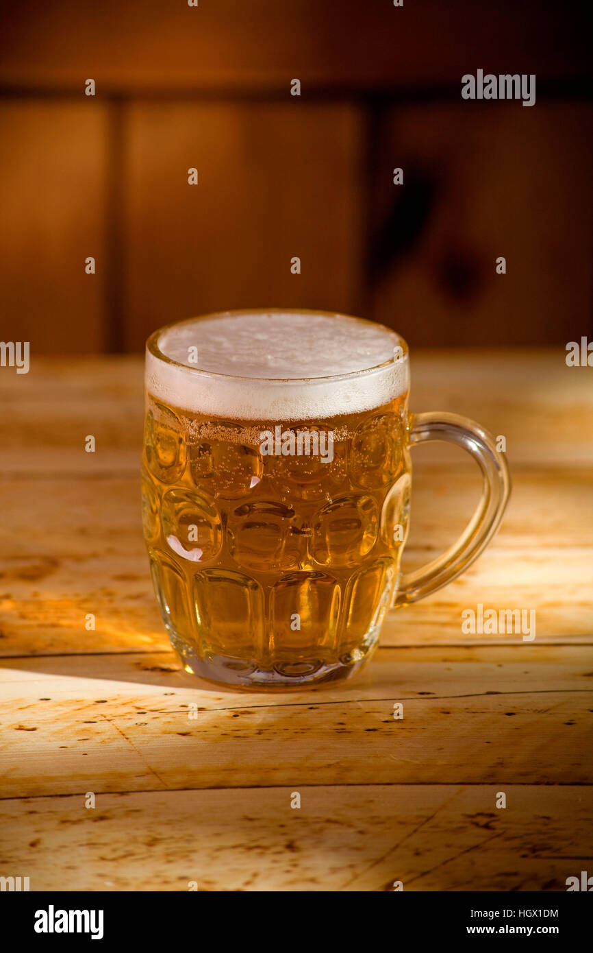 La pinta di birra sul tavolo con sole del pomeriggio la luce Foto Stock