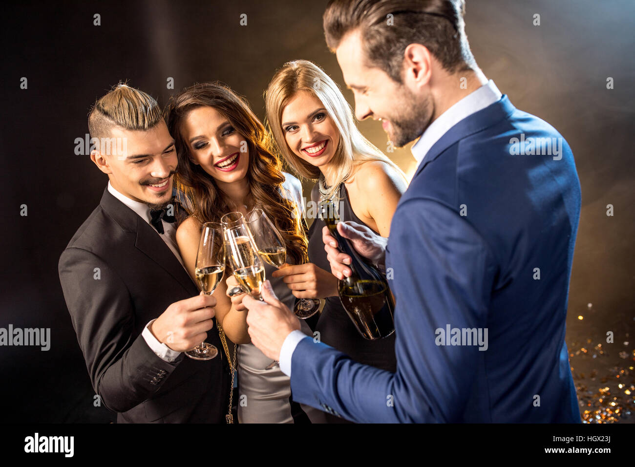 Felice giovani amici bevendo champagne e bicchieri tintinnanti Foto Stock