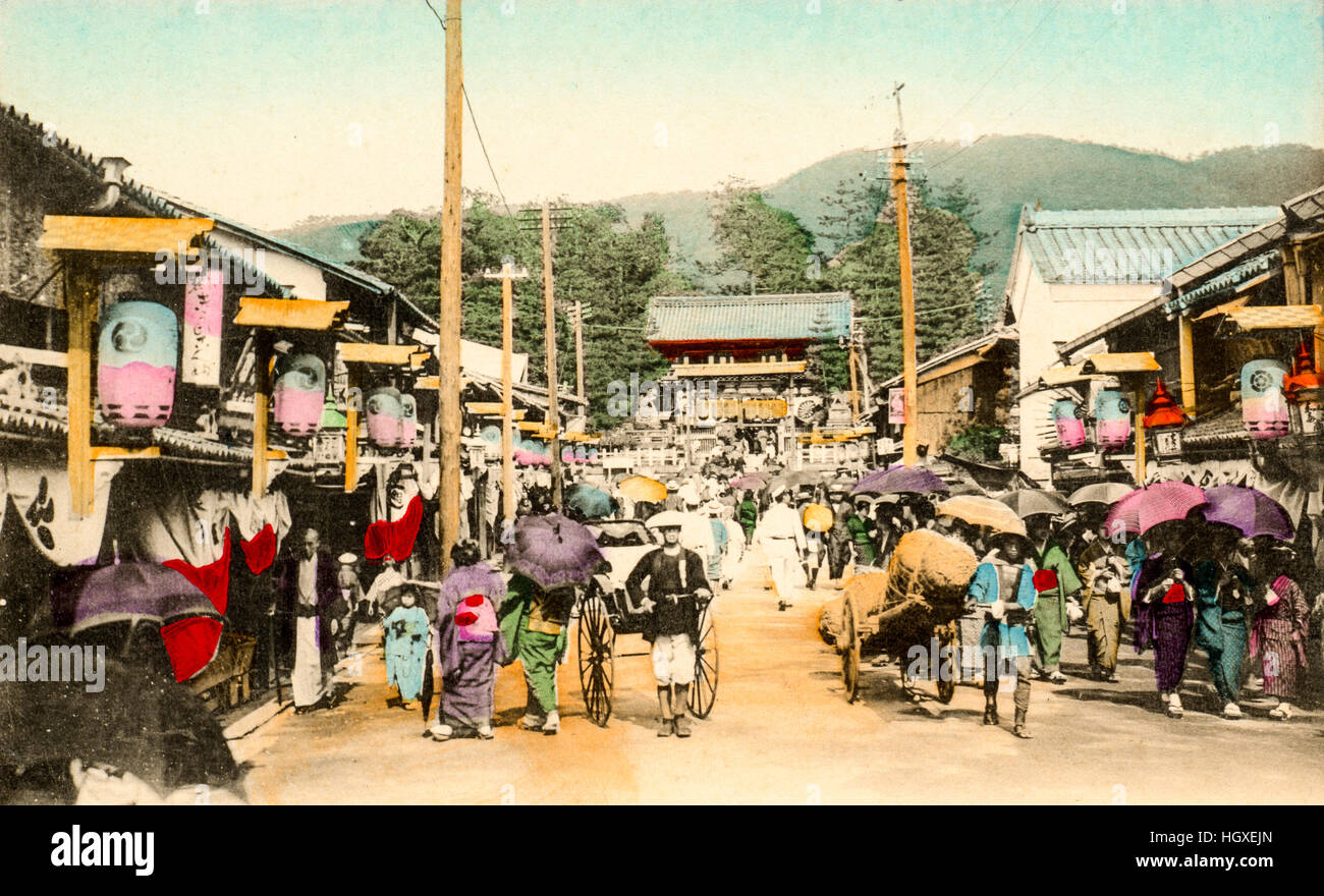 Giappone, Kyoto, Gion. Cartolina Vintage colorate a mano. Street, occupato con il popolo, con Yasaka-jinja Santuario gatehouse, mon, alla fine. affollate di persone Foto Stock