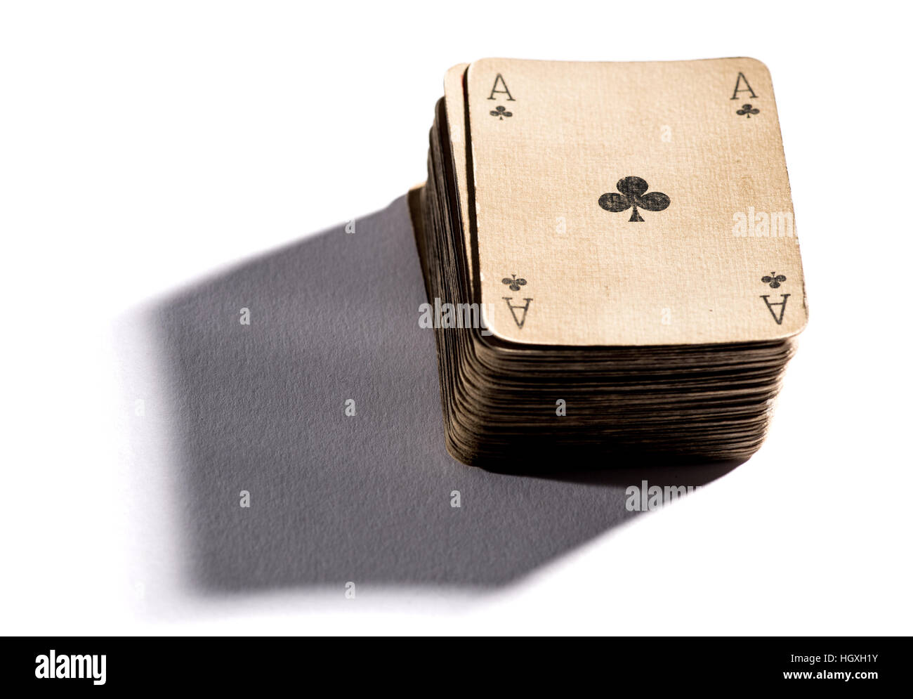 Mazzo di vintage vecchie carte da gioco di sbiadita della carta secca con l'asso del club sulla parte superiore, la caduta di ombra sulla superficie bianca Foto Stock