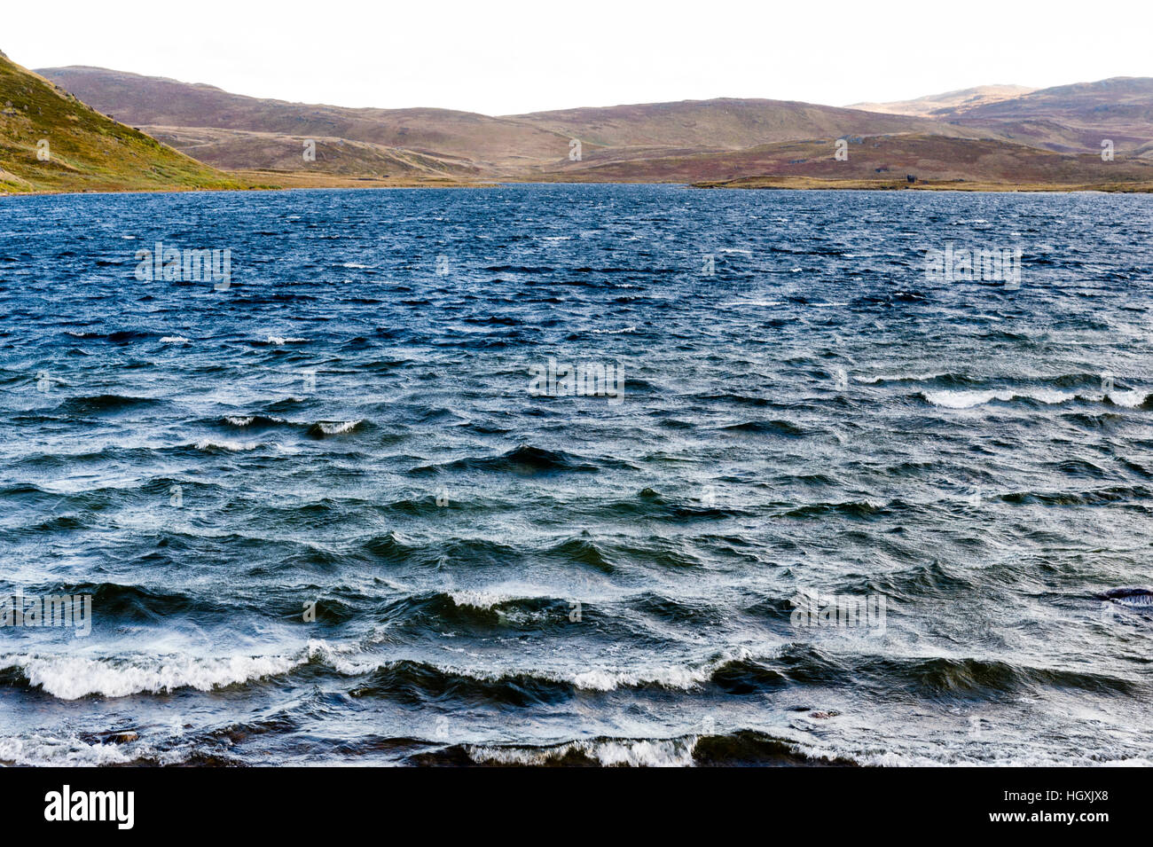 Onde sulla superficie spazzate dal vento di un lago alpino. Foto Stock