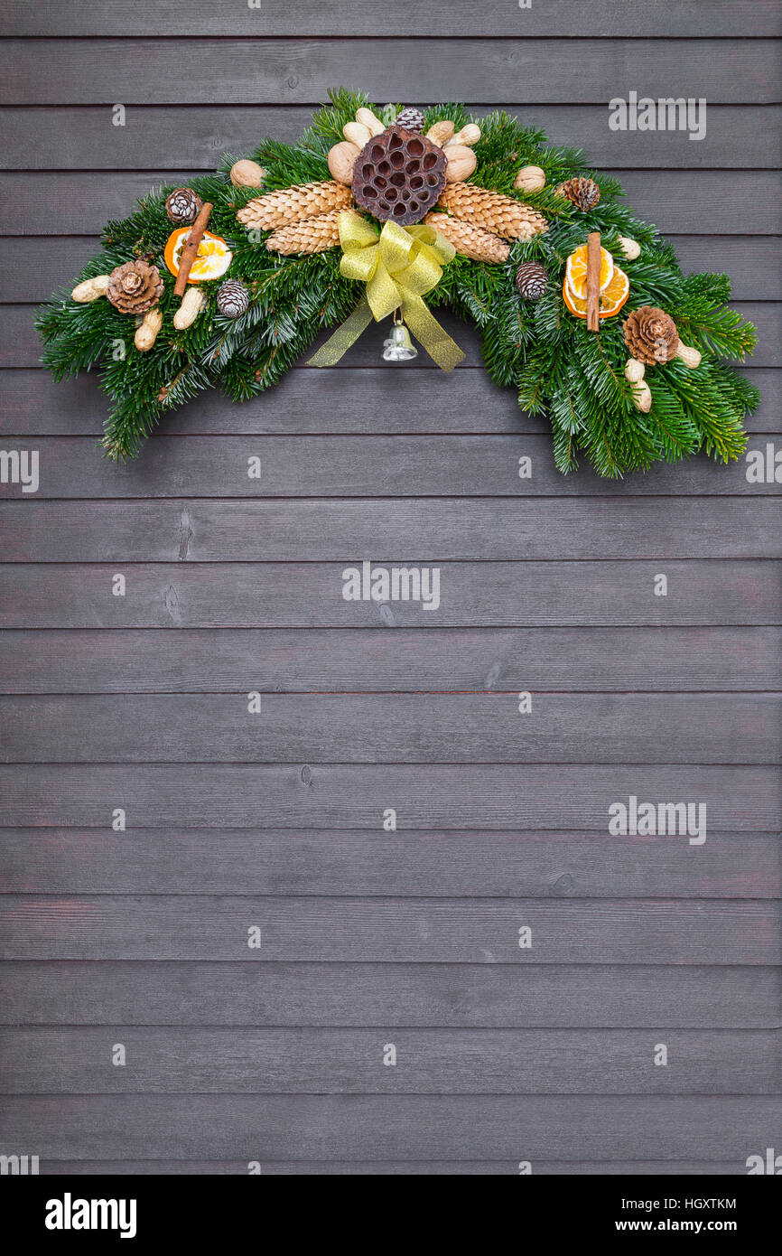 Il Natale e la ghirlanda invernale con prua giallo appeso sulla porta di legno scuro Foto Stock