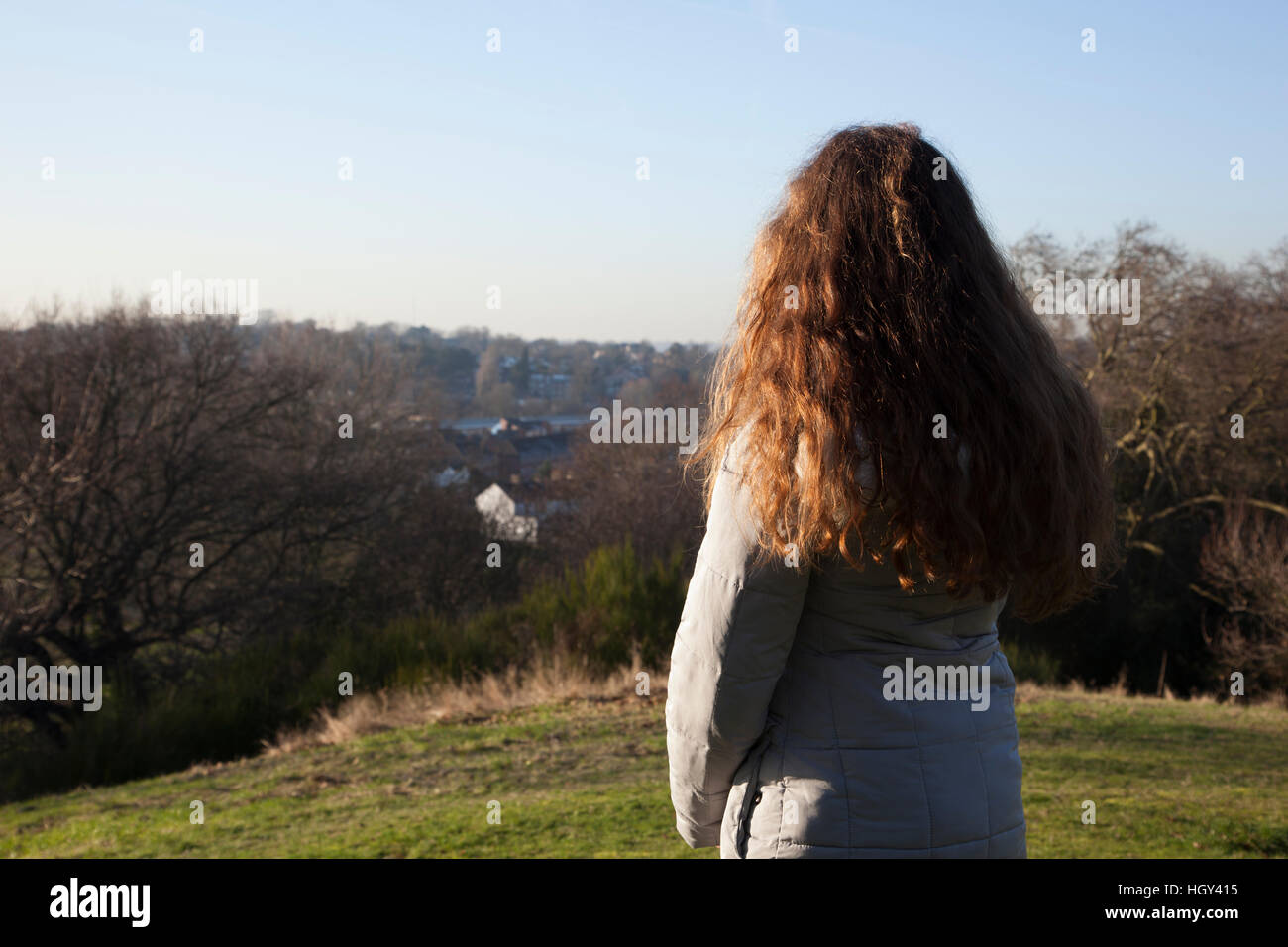 Vista posteriore di una donna in piedi da solo in una posizione tranquilla guardando in lontananza Foto Stock