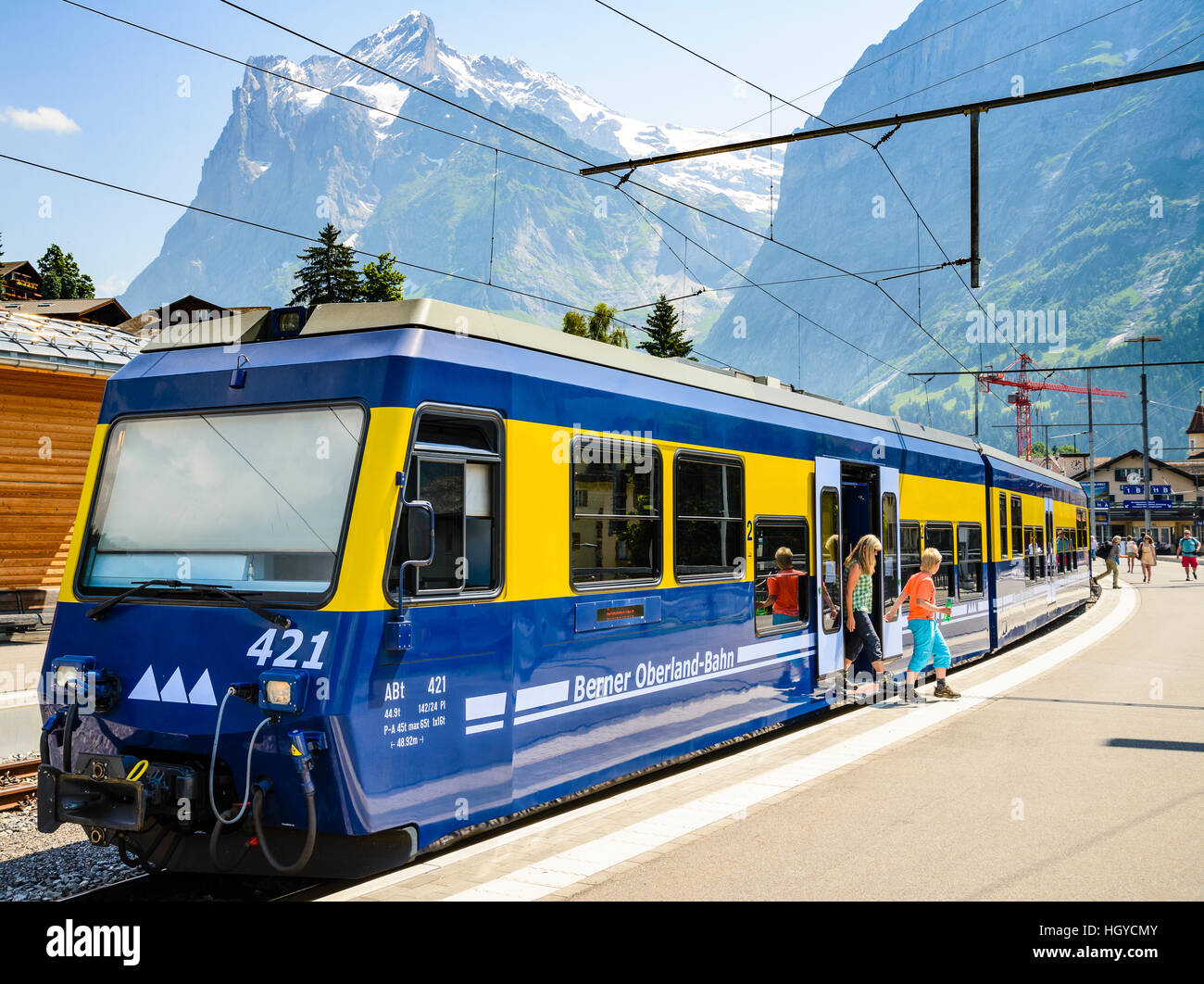 I bambini di lasciare un treno a Grindelwald in Svizzera con il Wetterhorn dietro di picco Foto Stock