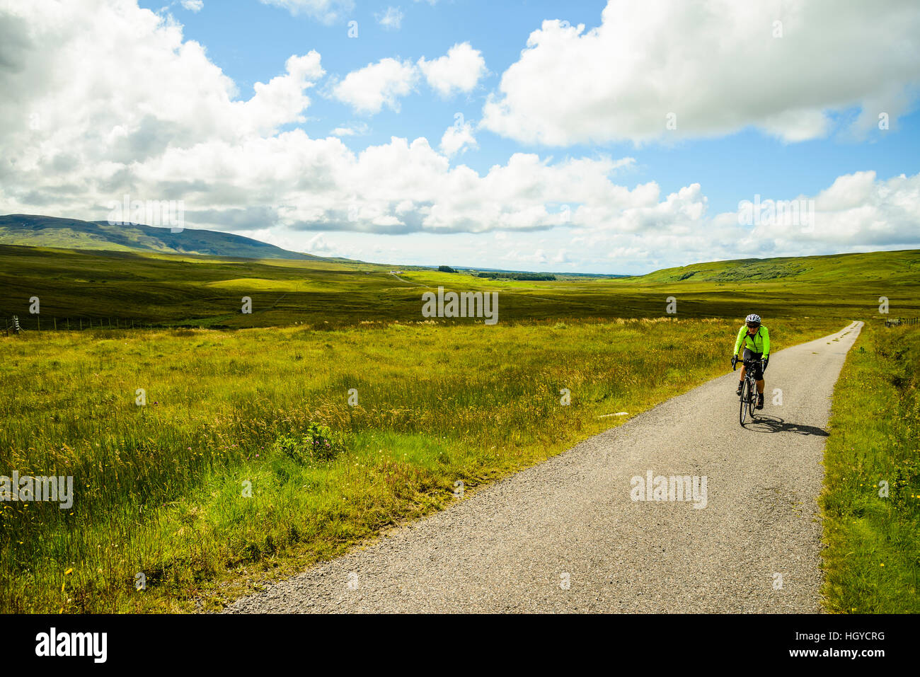 Femmina ciclista su strada vuota dell'isola di Islay Scozia Scotland Foto Stock