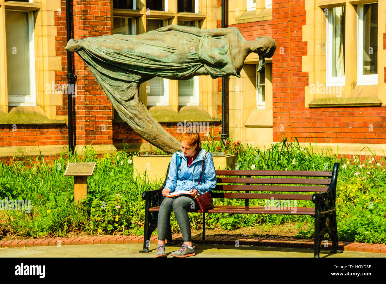 Studente legge davanti a 'Il Sognatore' una scultura da Quentin Campana in Clothworkers' Corte all Università di Leeds Foto Stock