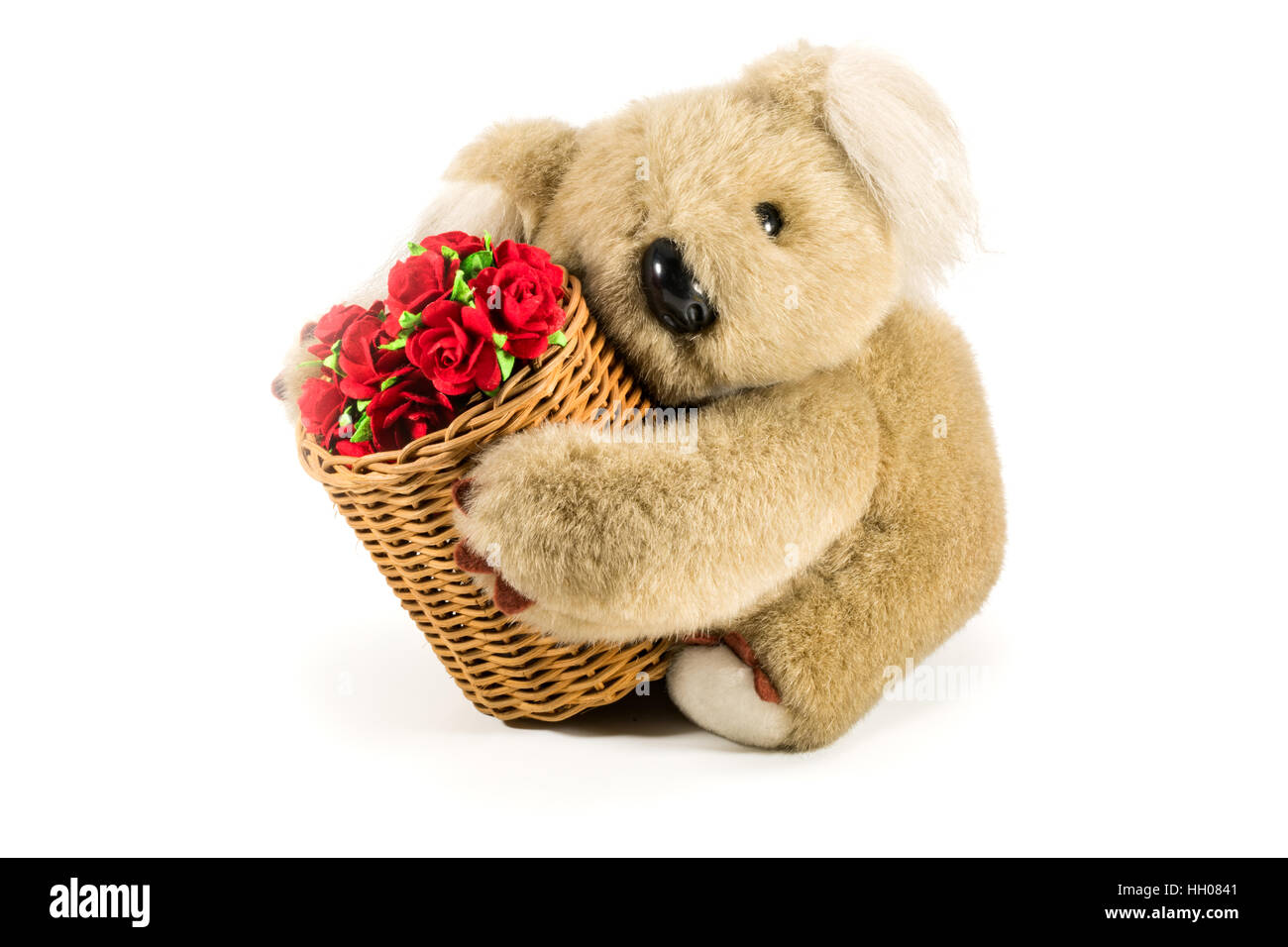 Orsacchiotto di peluche che trasportano il bambù cesto pieno di rose rosse su sfondo bianco Foto Stock