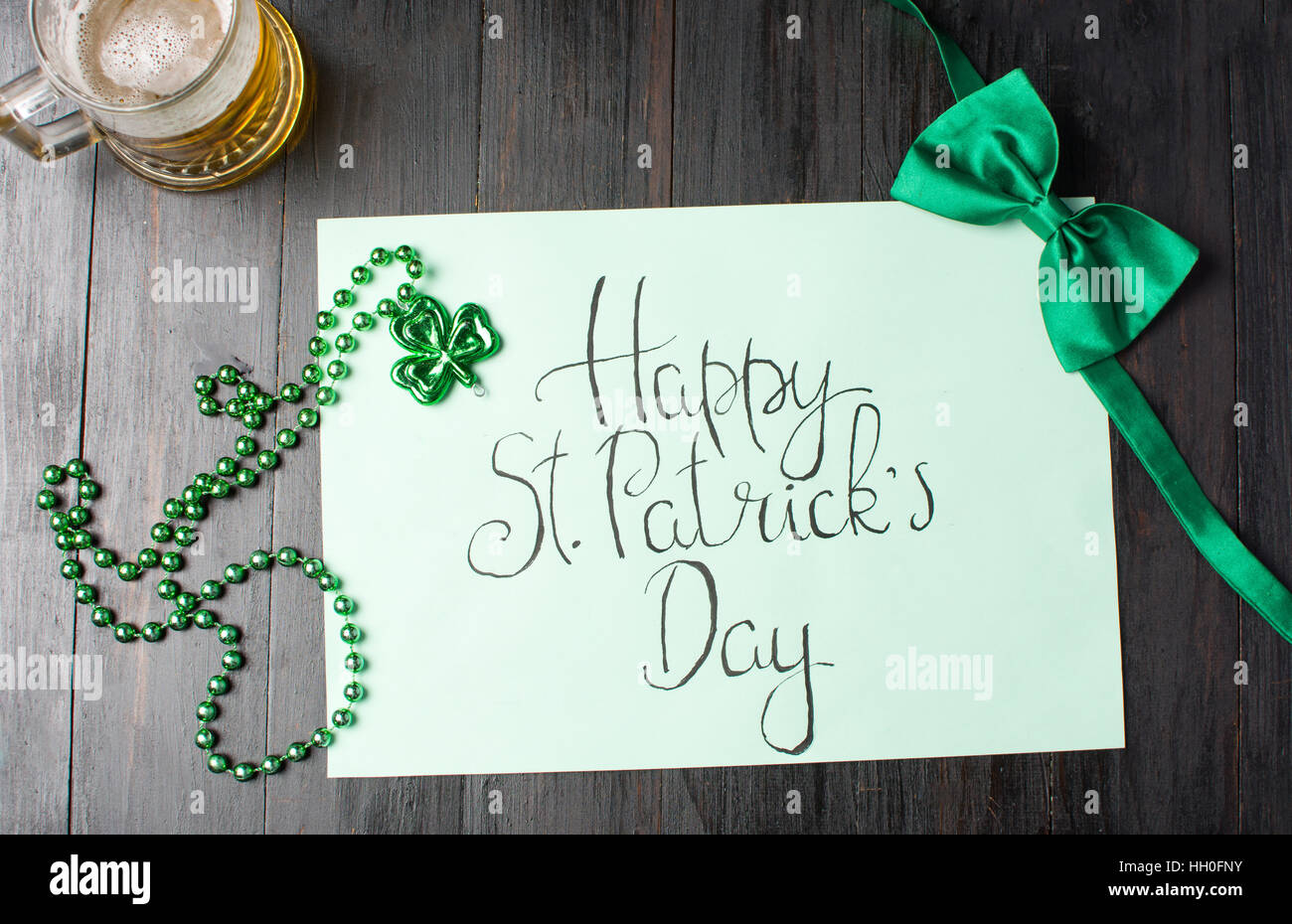 Happy St Patrick giorno scheda di calligrafia, verde accessori e una birra Foto Stock