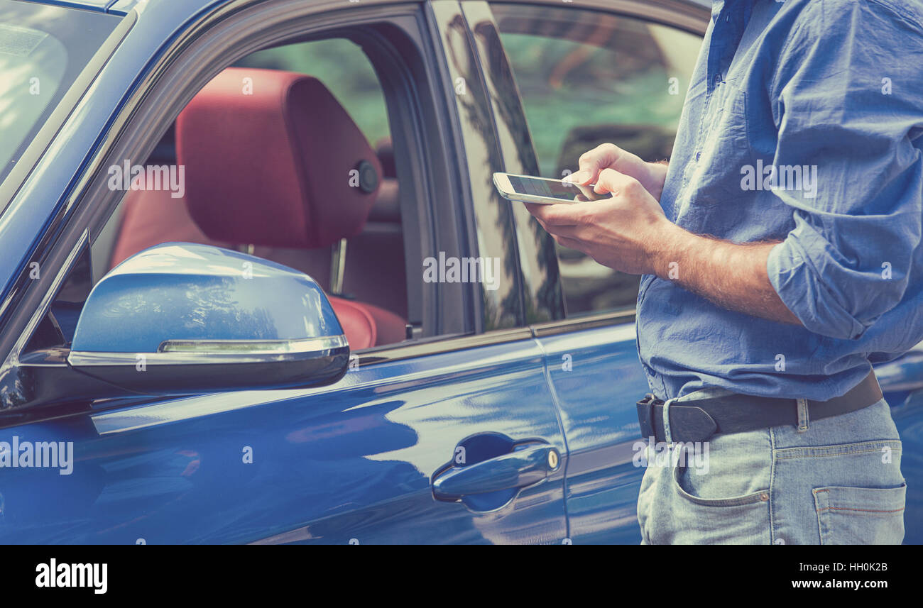 Telefono mobile app per i proprietari di auto concetto. Uomo che utilizza smart phone per controllare lo stato di controllo, la sua nuova vettura Foto Stock