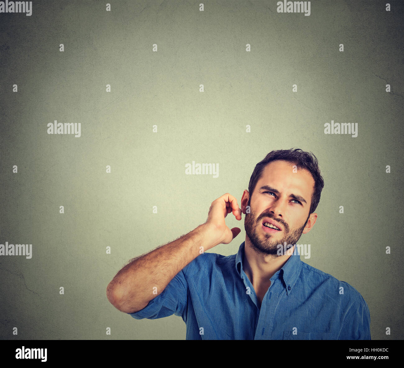 Uomo di graffiare la testa, pensare profondamente su qualcosa, guardando in alto, isolato su sfondo grigio. Un'espressione facciale umana, emozione Foto Stock