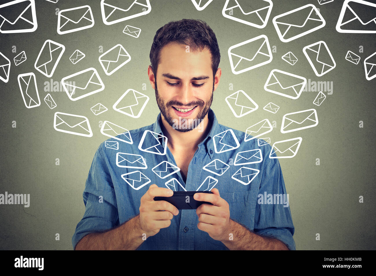 Uomo felice occupato per inviare i messaggi e-mail sul telefono intelligente icone di posta elettronica in uscita battenti di telefono cellulare isolato su sfondo grigio Foto Stock