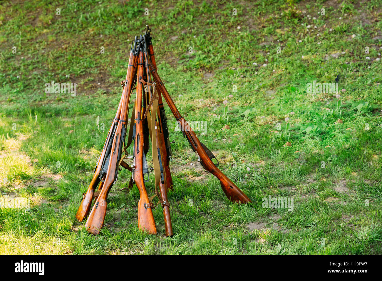 I fucili disposte in una forma a piramide. L'arma Installazione su erba verde dello sfondo. Foto Stock