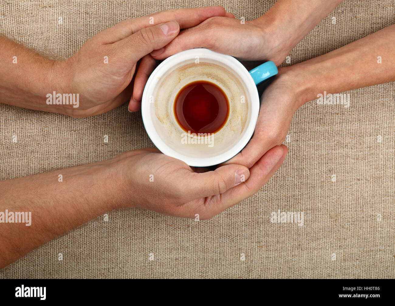 L uomo e la donna mani e abbracciando insieme vuoto grande tazza di caffè nero su tela tovaglia, close up, elevati vista superiore Foto Stock