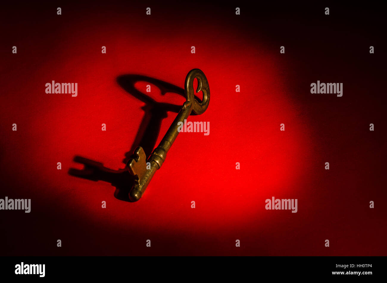 Uno scheletro chiave su sfondo rosso con ombre e spazio per testo o copiare Foto Stock