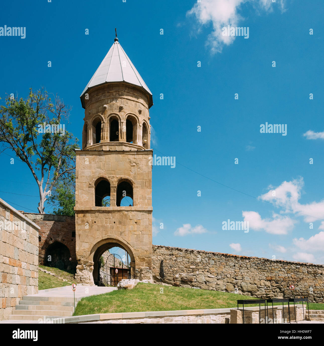 Mtskheta, Georgia. Il Three-Storey Campanile al monastero di Samtavro Area complessa con muro di pietra nella soleggiata giornata sotto il blu cielo nuvoloso. Foto Stock