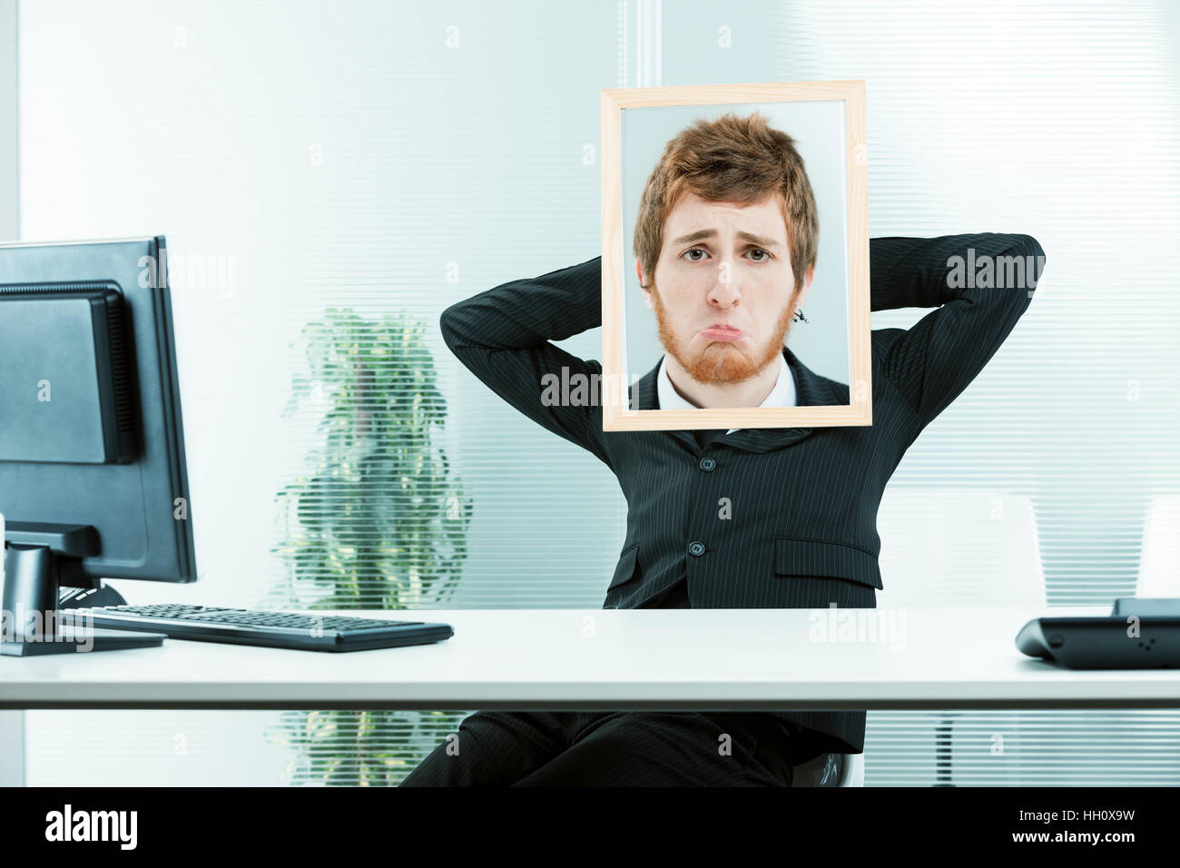 Lavoratore di ufficio con le sue braccia rilassata e una cornice con una foto di un altro volto con una espressione triste Foto Stock