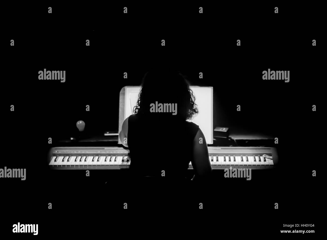 Silhouette di donna che gioca a un organo pianoforte Foto Stock