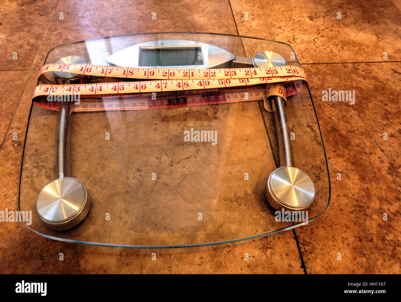 Scala per peso del monitor con un nastro di misurazione per prendere le misure per tenere traccia della forma fisica Foto Stock
