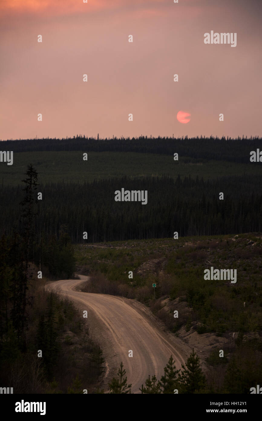 Il sole tramonta attraverso fumo spesso da un incendio in un bosco vicino al Prince George, BC, Canada. Foto Stock