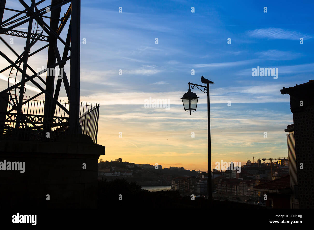 Silhouette di lampada con bird sullo sfondo della città e il crepuscolo blue sky. Foto Stock