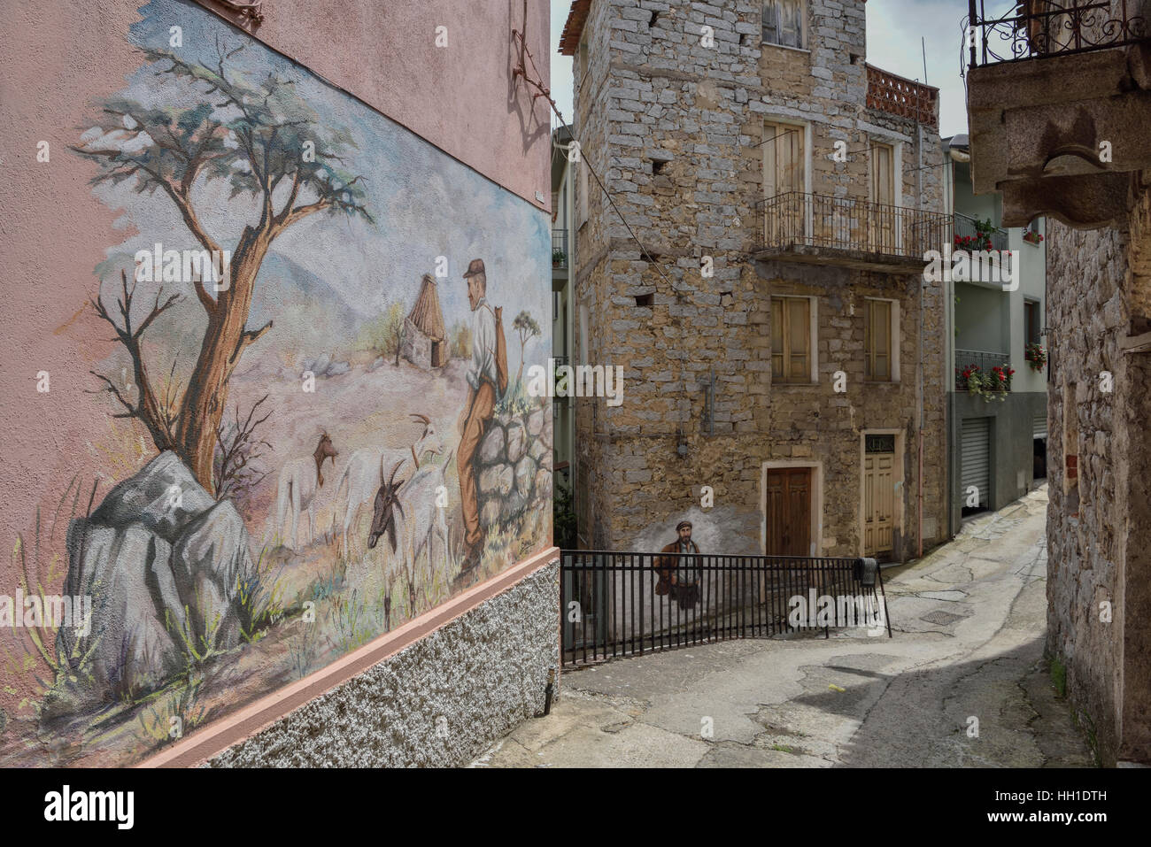Alley con murale del pastore sardo, artista Pasqualino Baingiu, Orgosolo, Provincia di Nuoro, Sardegna, Italia Foto Stock