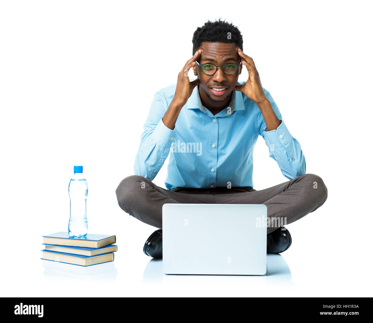African American college studente con mal di testa seduto su sfondo bianco con laptop e alcuni libri Foto Stock
