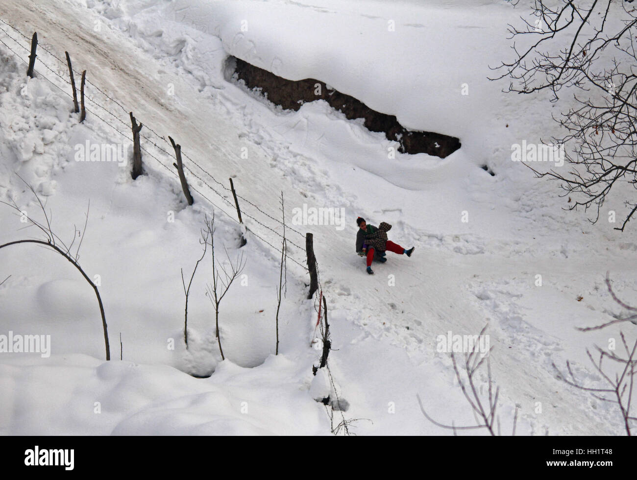 Srinagar, India. 15 gennaio, 2017. I bambini del Kashmir giocando slitte su terreni sdrucciolevoli strade coperte di neve a Tangmarg area in indiano Kashmir controllato su Domenica, 15 gennaio 2017. Ondata di freddo intensificato nella valle del Kashmir dall'ultimo tre settimane mentre il meteorologo predice più piogge o neve nelle prossime 24 ore. Credito: Umer Asif/Pacific Press/Alamy Live News Foto Stock