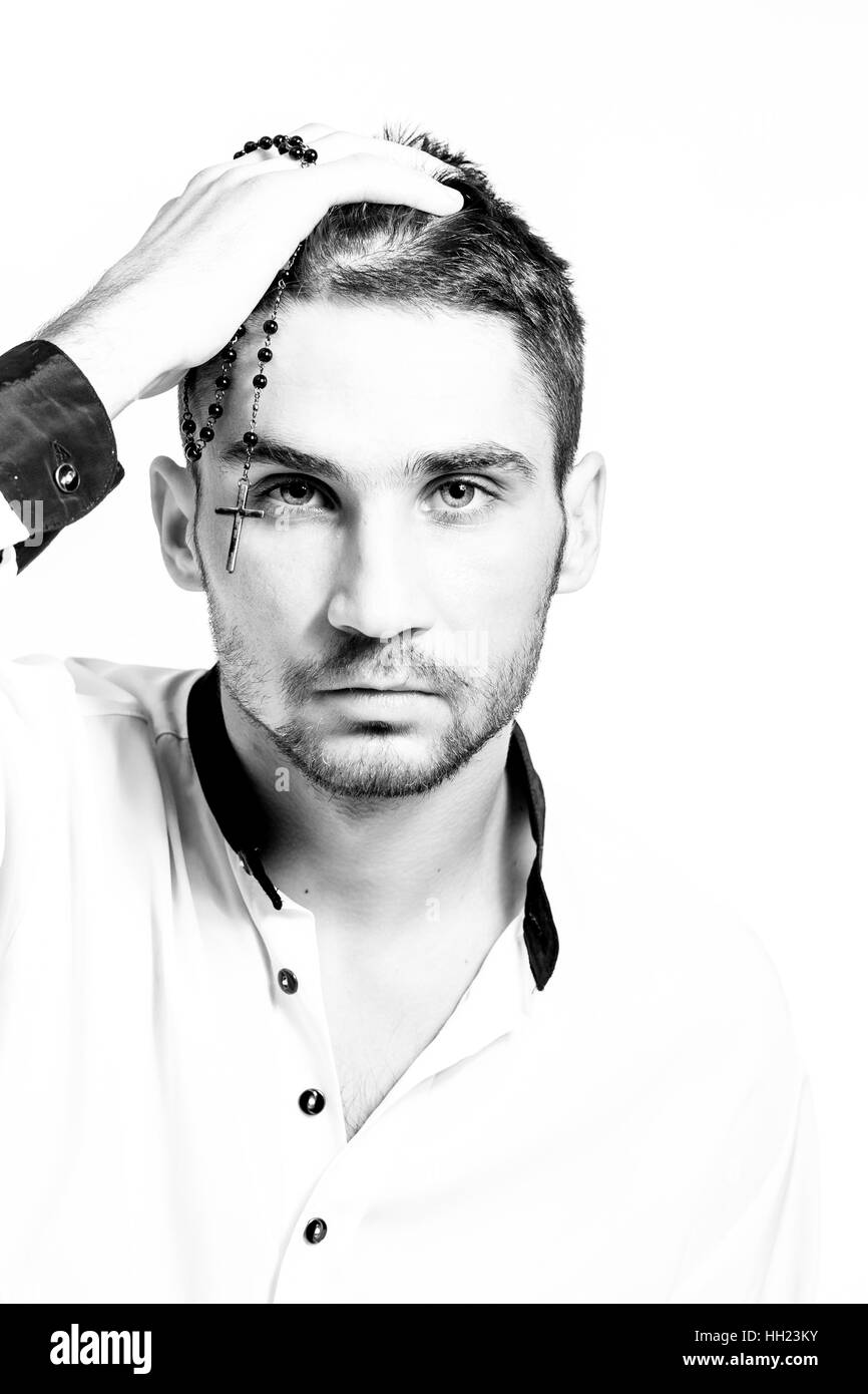 Uomo con Rosario con una croce tenendo la sua testa. Difficoltà di fede. Close-up verticale. Chiave di alta. Foto Stock