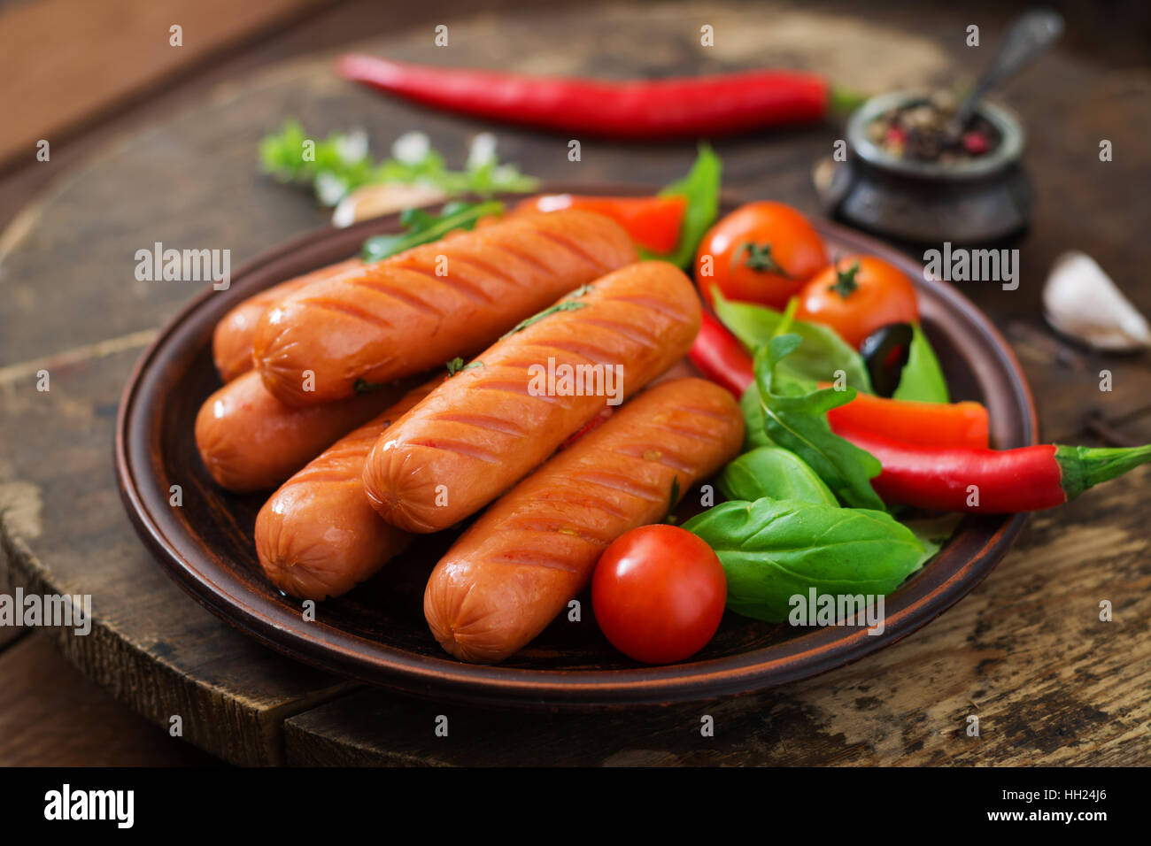 Salsicce alla griglia e verdura su uno sfondo di legno in stile rustico. Foto Stock