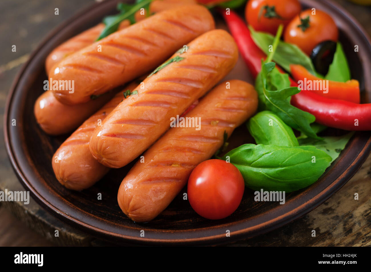 Salsicce alla griglia e verdura su uno sfondo di legno in stile rustico. Foto Stock