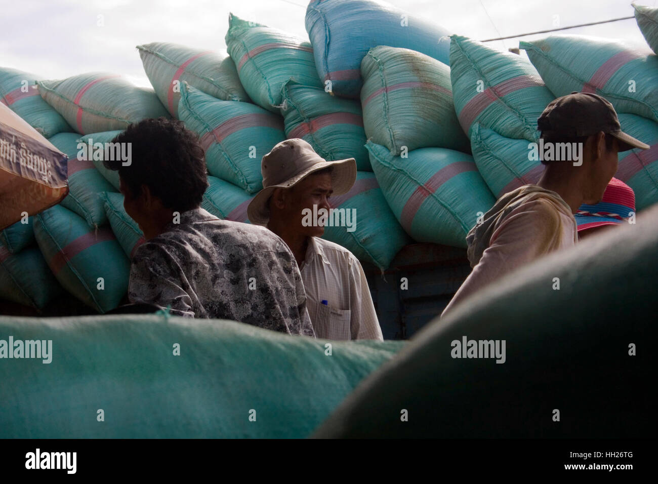 Gli uomini sono lo scarico dei sacchi di raccolta unmilled riso da un camion prima di essere pesati su una bilancia nel villaggio di Chork, Cambogia. Foto Stock