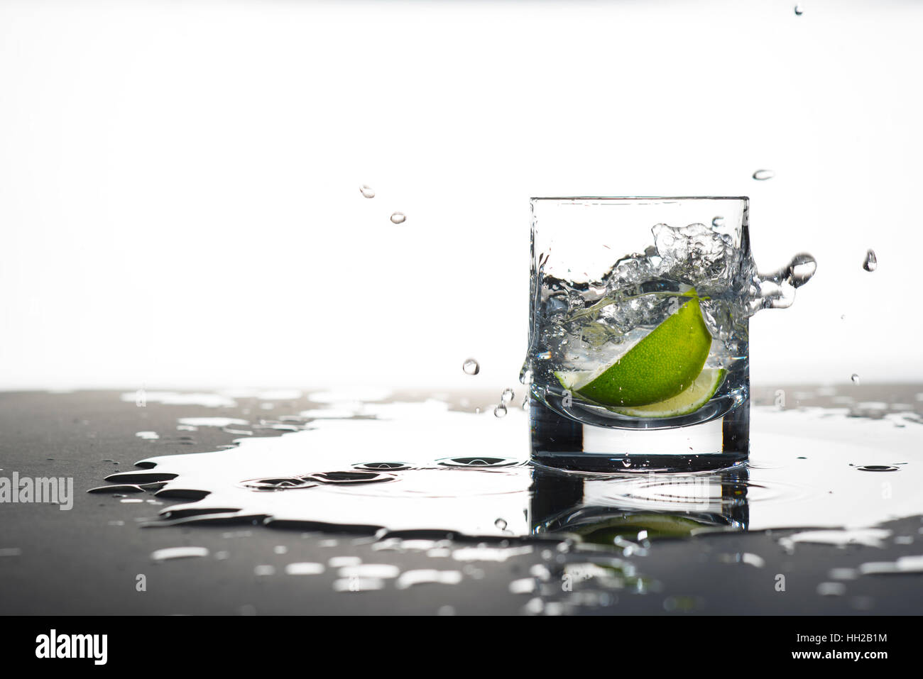 Spicchi di lime gocciolata in un bicchiere Foto Stock