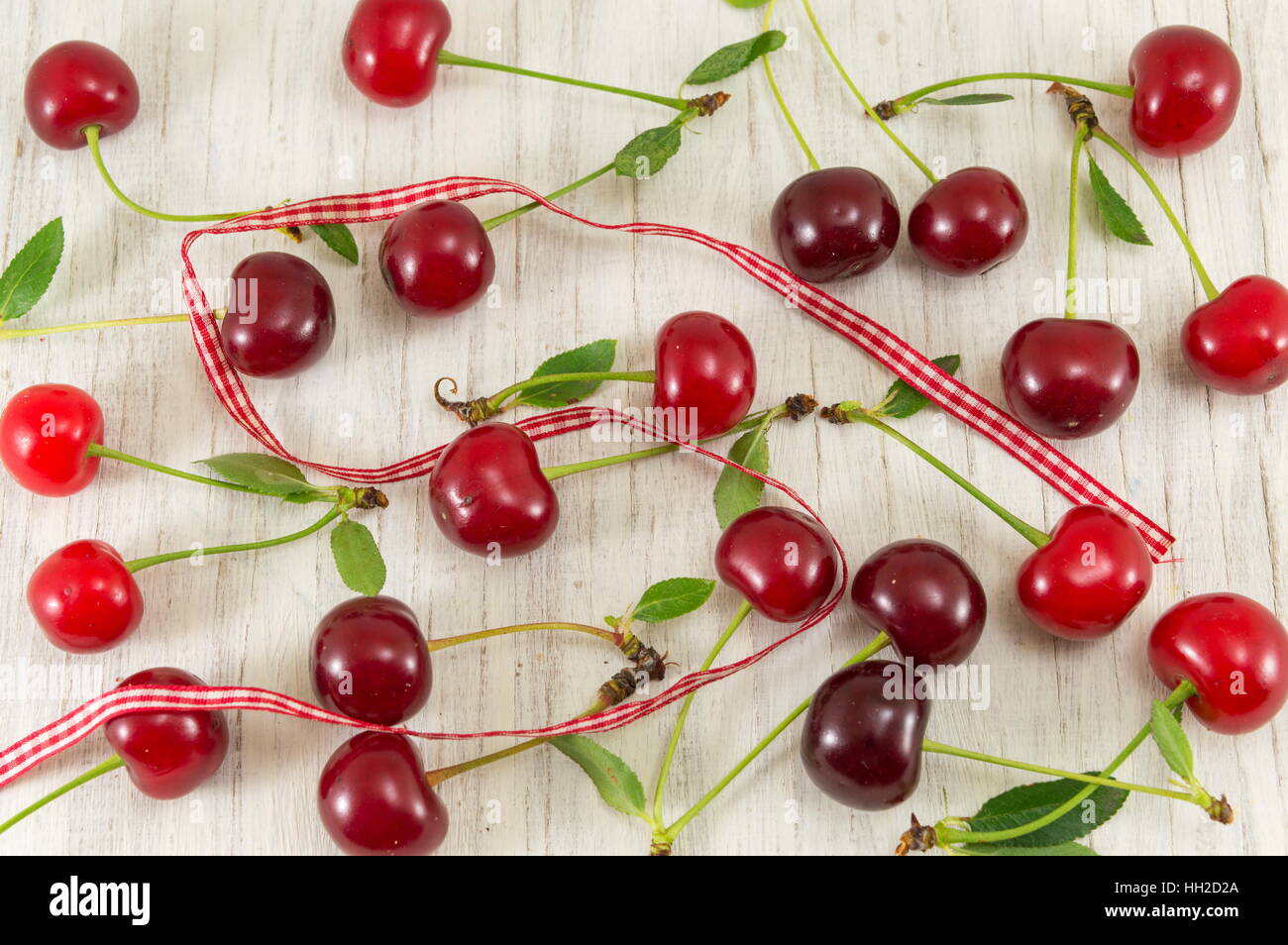 Grappolo di ciliege rosse sparse su un tavolo di legno Foto Stock
