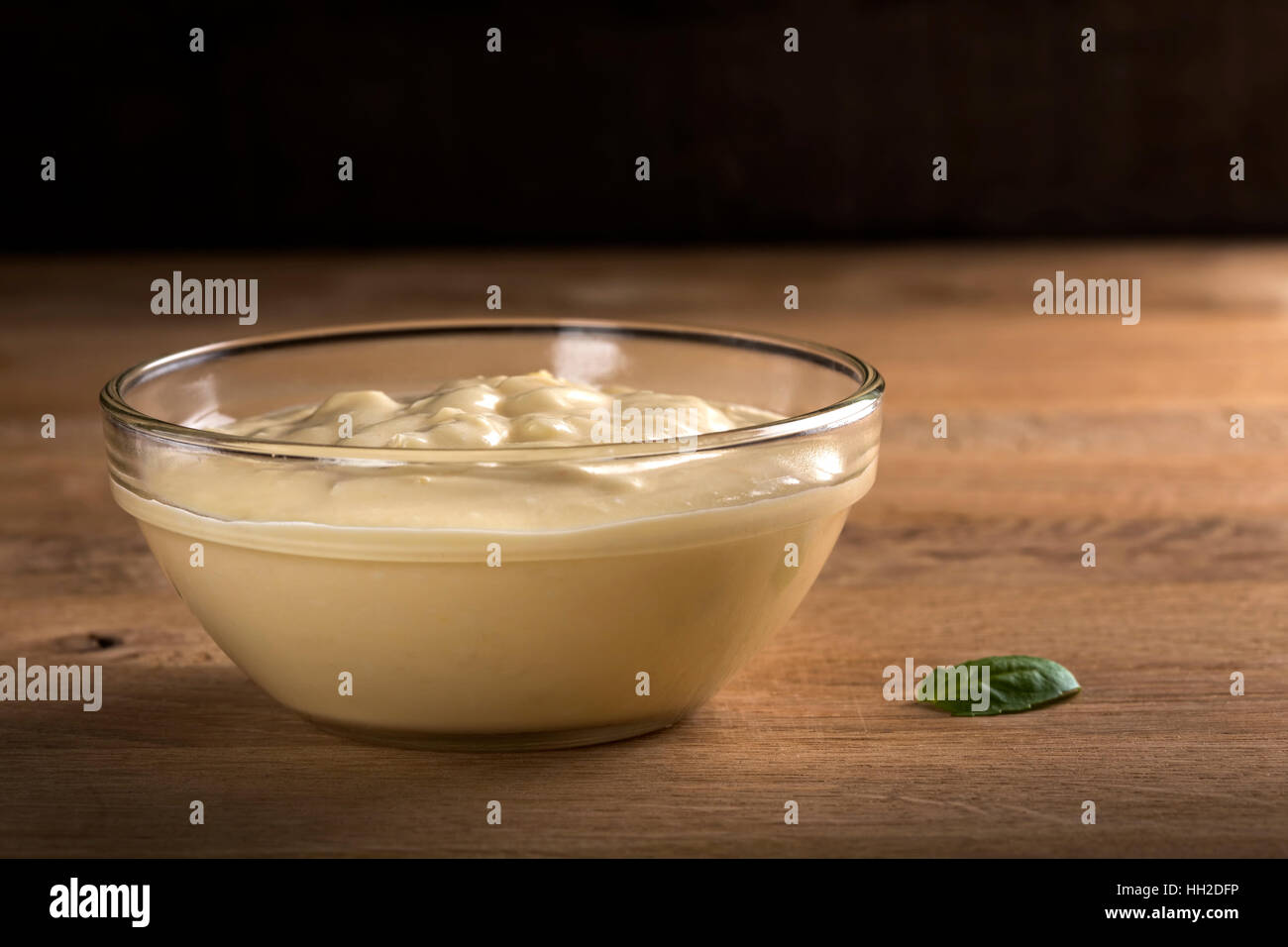 Vaschetta trasparente riempita di fatto in casa la maionese su sfondo di legno Foto Stock