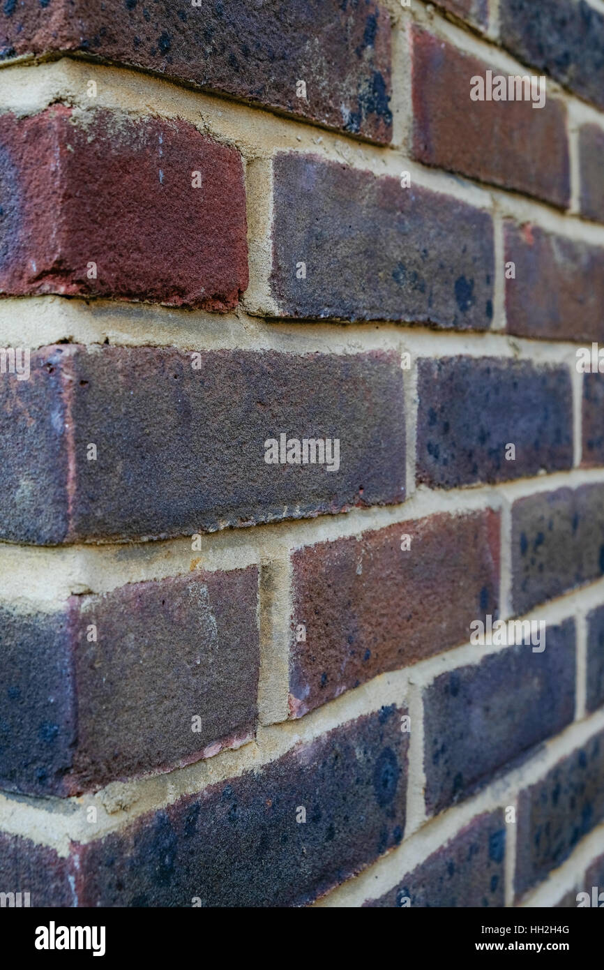 Colpo verticale di un muro di mattoni, closeup mostra mattoni stock con puntamento bianco. Nuovo in mattoni rossi e viola. Foto Stock
