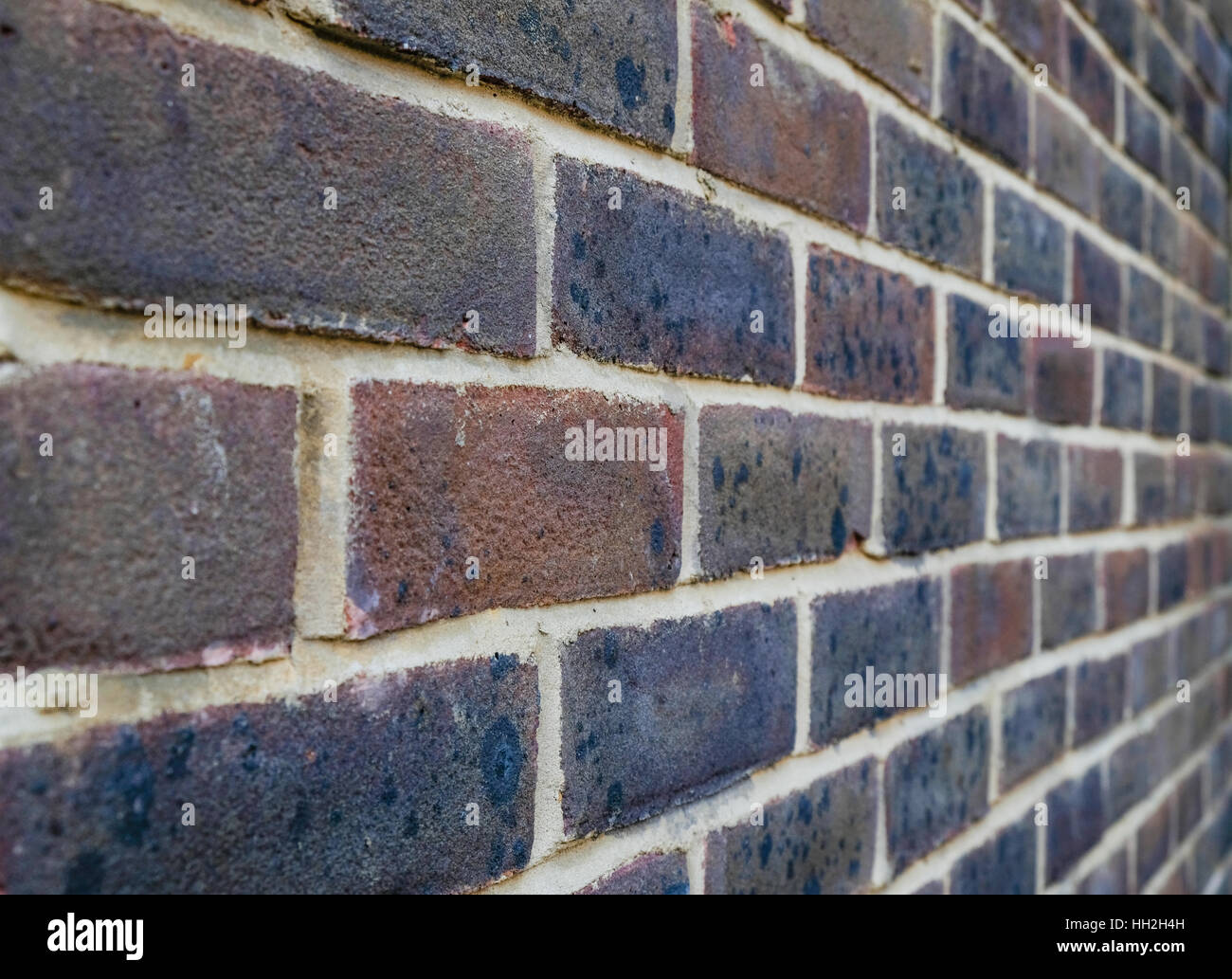Inquadratura orizzontale di un muro di mattoni, closeup mostra mattoni stock con puntamento bianco. Nuovo in mattoni rossi e viola. Foto Stock