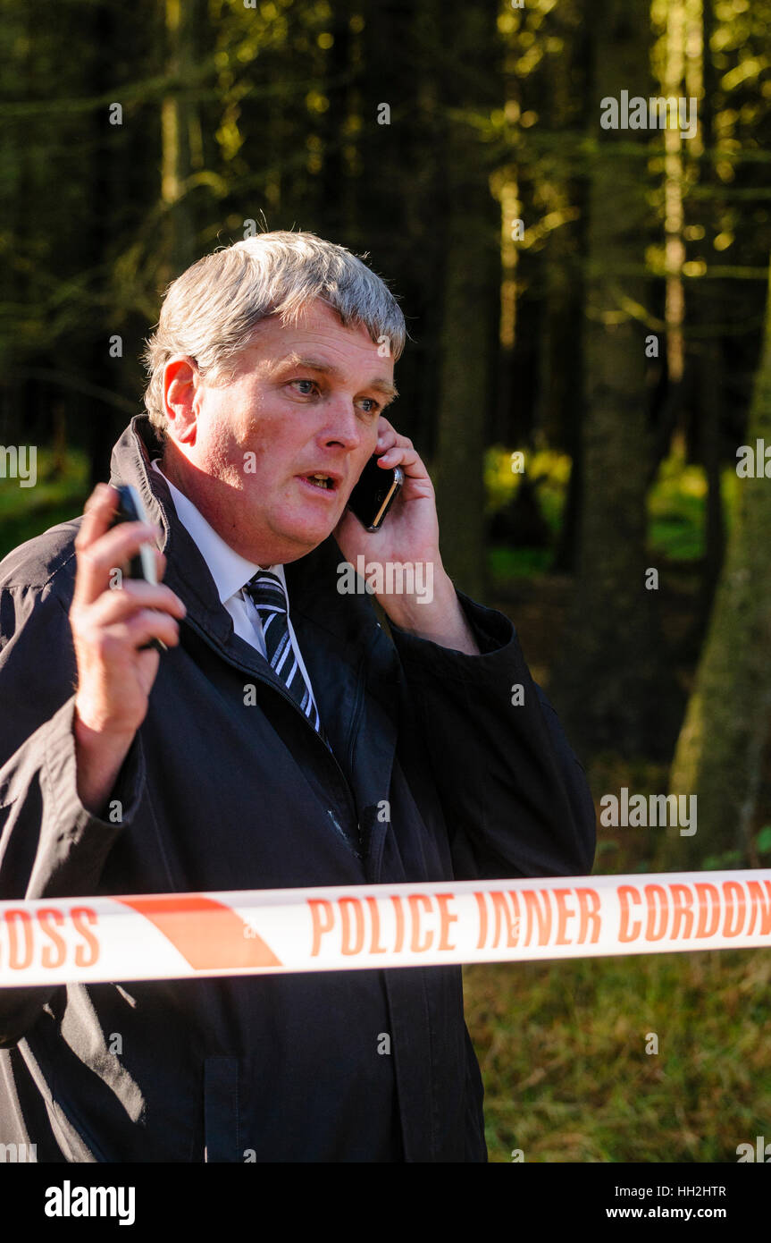 Jim Wells, MLA, (DUP) a parlare su un telefono cellulare mentre in corrispondenza di un cordone di polizia. Foto Stock