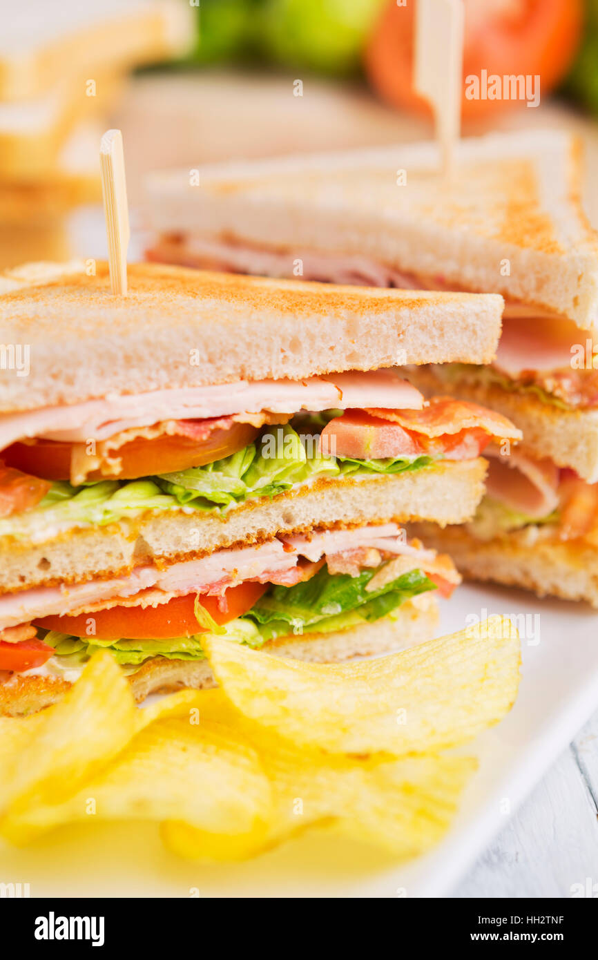 Un club sandwich su un tavolo rustico in condizioni di luce intensa. Foto Stock