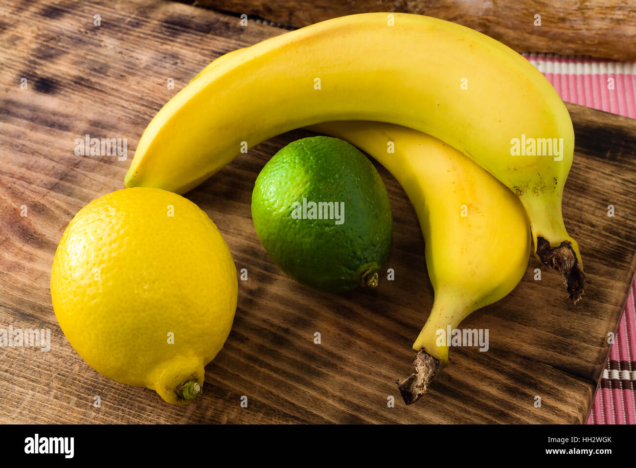 Fresche e mature, agrumi, limone e calce, insieme con le banane sul bordo di taglio. Foto Stock