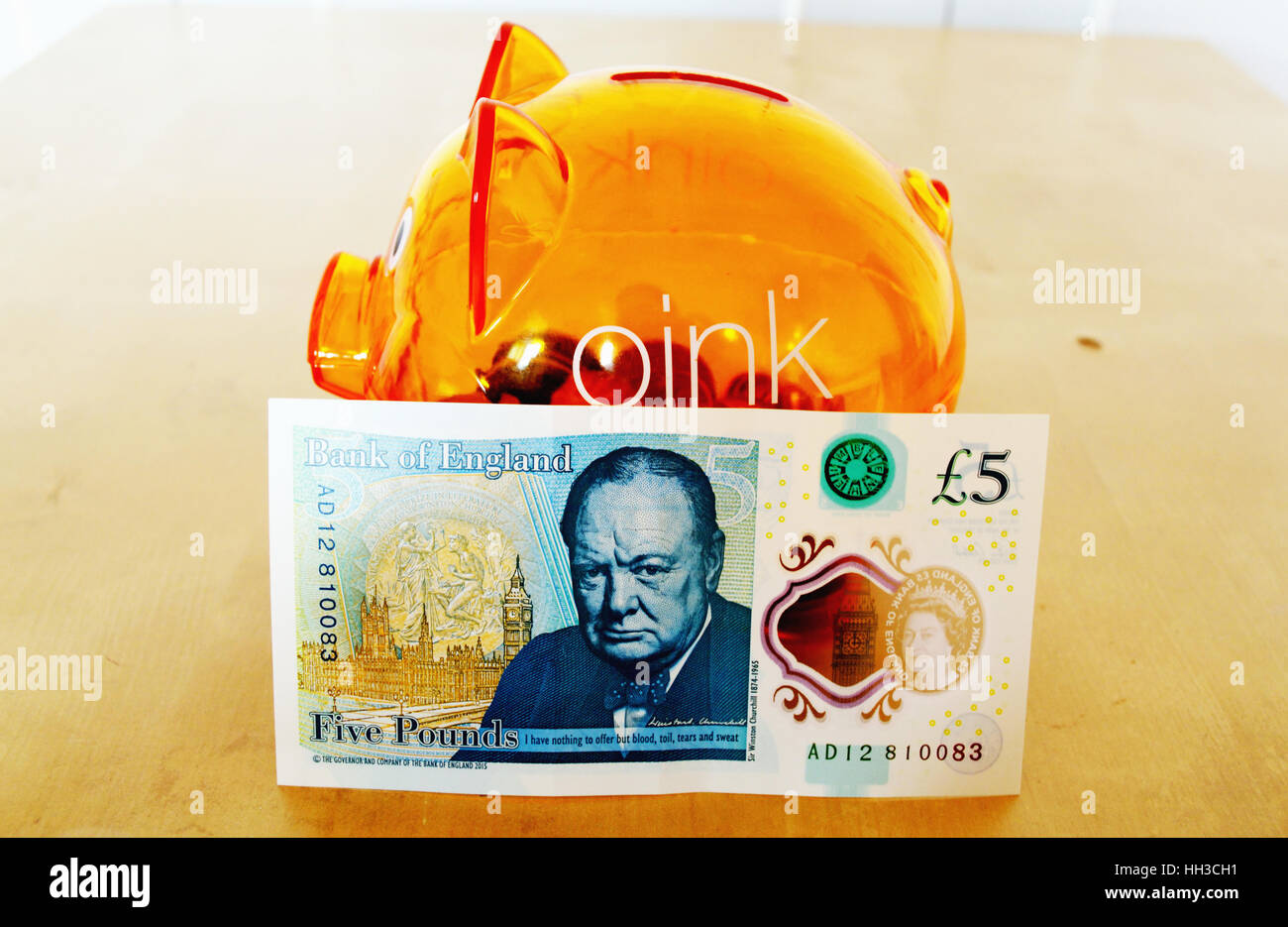 Retro del nuovo polimero REGNO UNITO cinque pound nota appoggiata contro un arancio salvadanaio Foto Stock