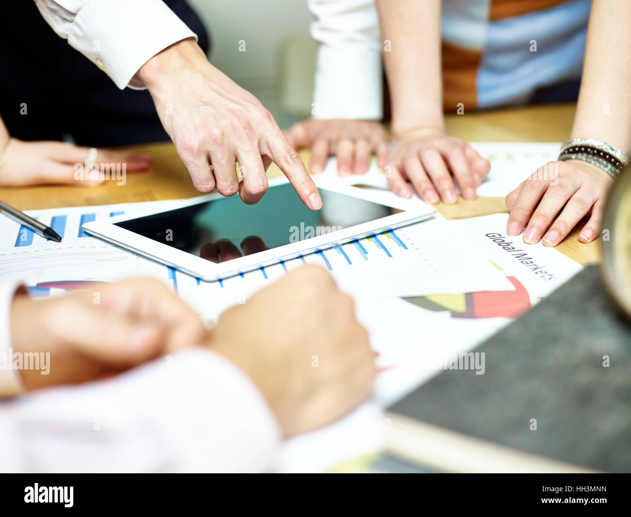Gruppo di popoli asiatici riuniti a discutere di office business plan utilizzando computer tablet. Foto Stock