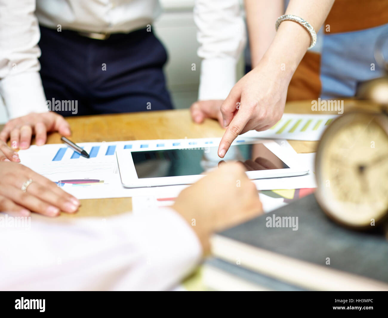 Gruppo di popoli asiatici riuniti a discutere di office business plan utilizzando computer tablet. Foto Stock