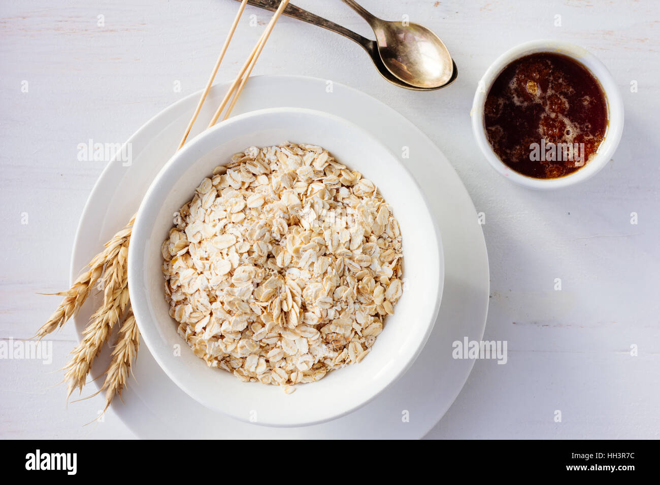 Farina di avena in bianco ciotola e miele top view il fuoco selettivo Foto Stock