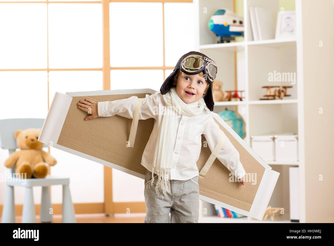 Ragazzo bambino vestito come pilota o aviatore gioca con la carta a mano le  ali nella sua stanza Foto stock - Alamy