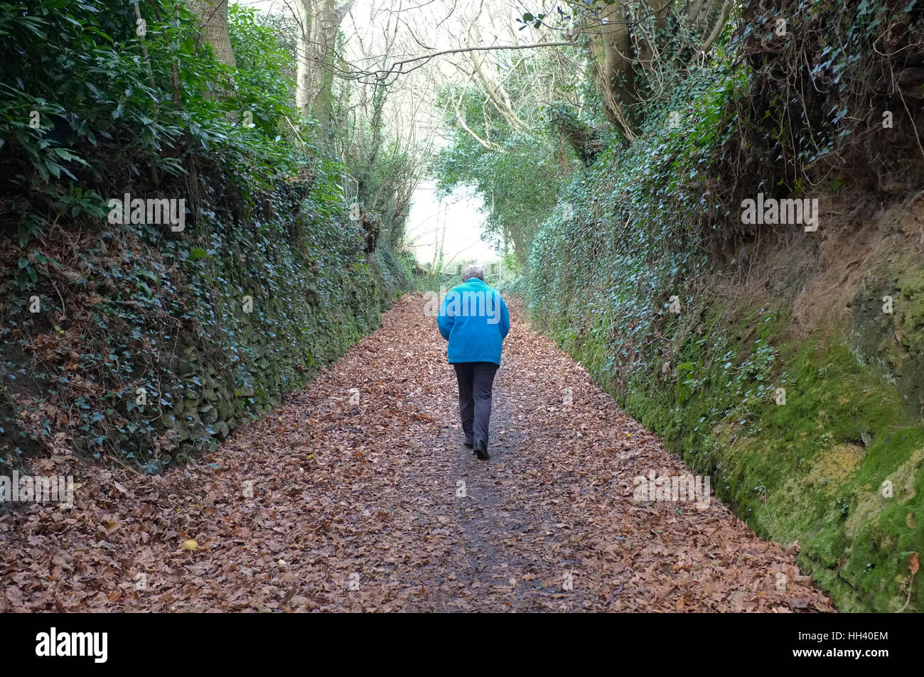 Un pensionato di lady camminando lungo una strada di campagna Foto Stock